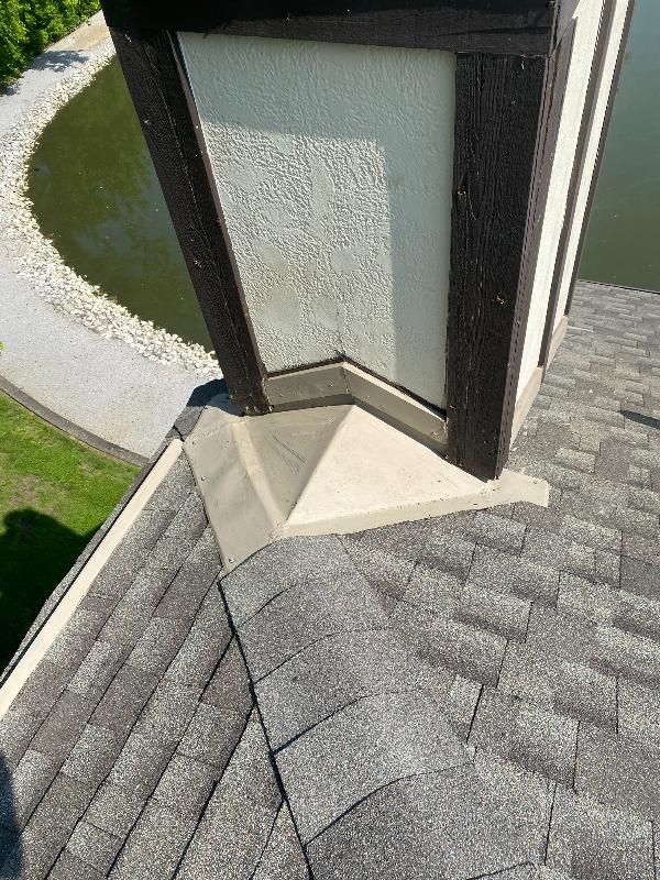 A chimney on top of a roof next to a body of water.