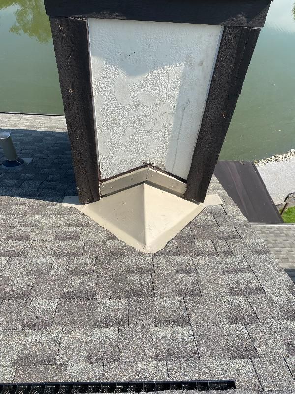 A lamp post is sitting on top of a roof next to a body of water.