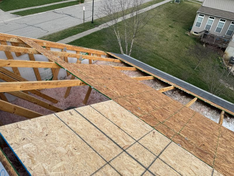 The roof of a house is being built and the roof is covered in plywood.