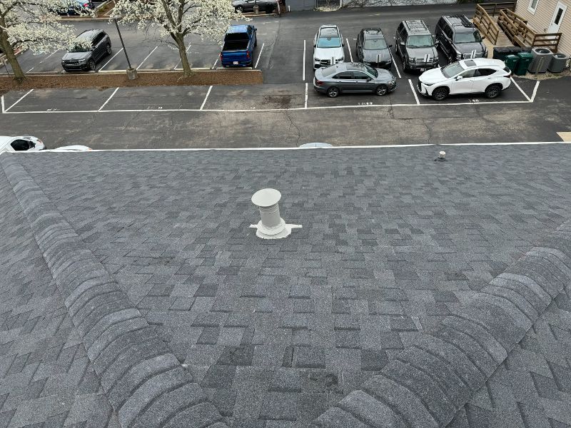 A parking lot with cars parked in it and a roof with a vent on it.