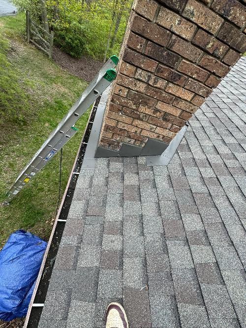 A person is standing on a roof next to a chimney.