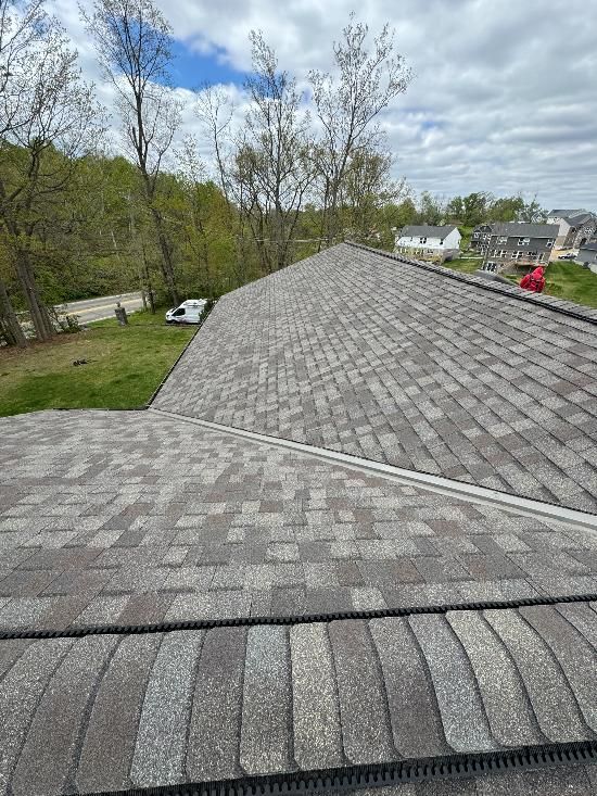 A roof with a lot of shingles on it and trees in the background.