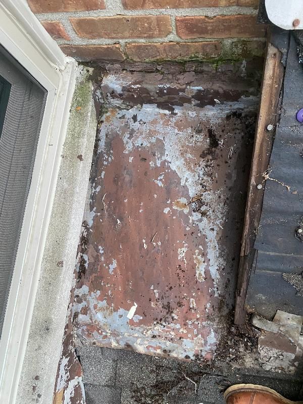 A piece of wood is sitting on the ground next to a brick wall.