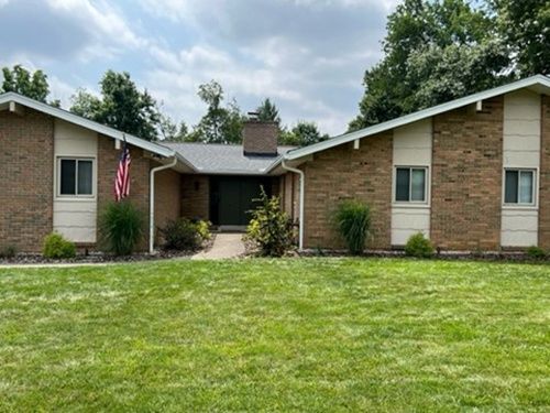 A brick house with a large lawn in front of it