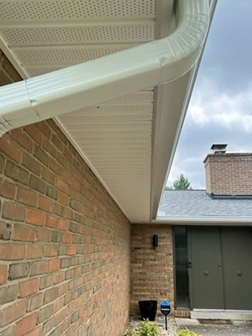 There is a white gutter on the side of a brick house.