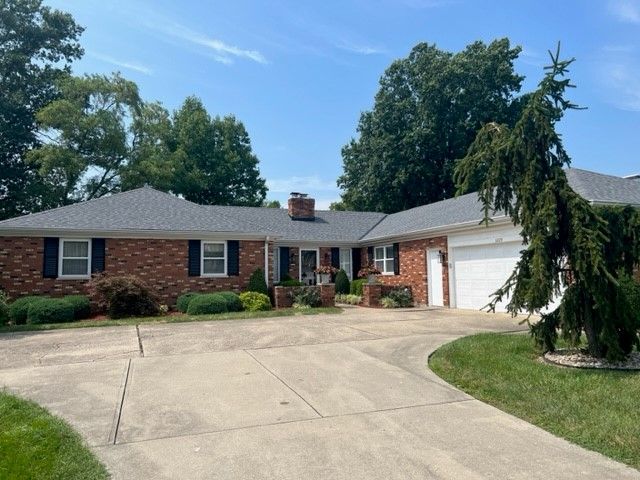 A brick house with a gray roof and a white garage