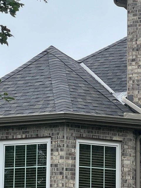 A brick house with a gray roof and white windows