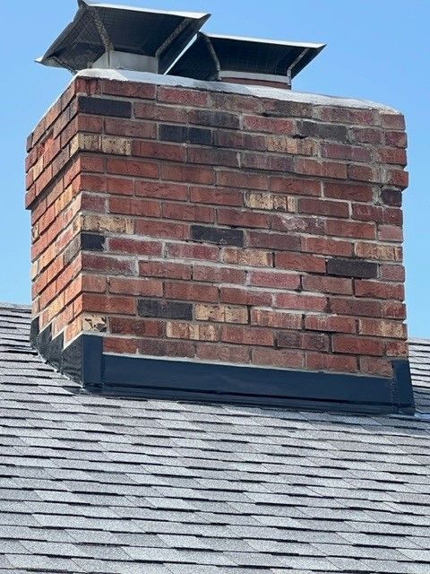 A brick chimney is sitting on top of a roof.