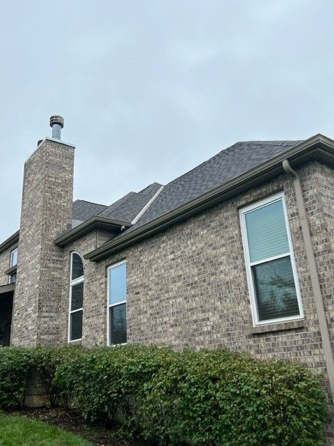 A large brick house with a chimney and a lot of windows.