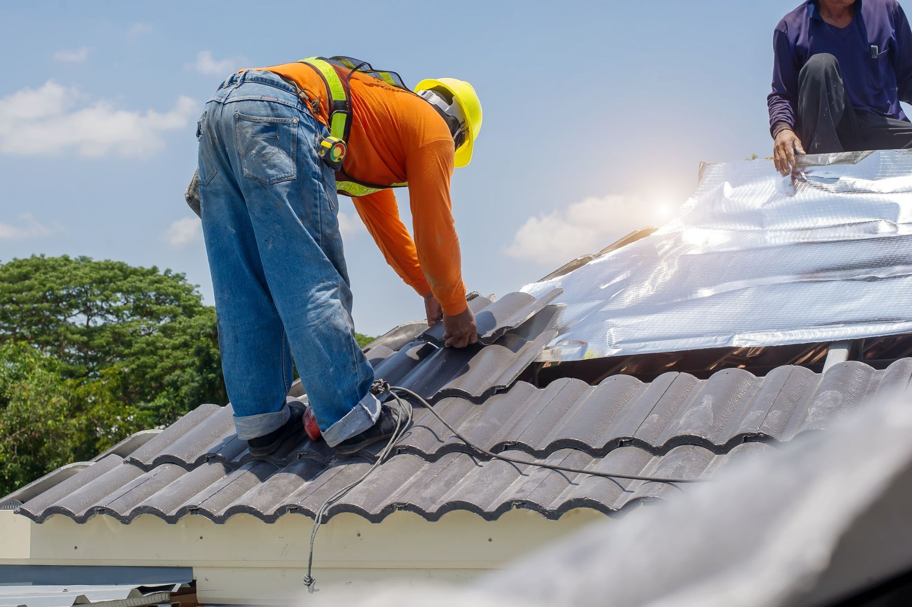 Two men are working on the roof of a house.