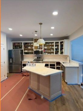 Modern kitchen with island, stainless fridge, white cabinets, and red runner on wood floor