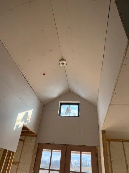 Interior of a small cabin with a high vaulted ceiling and windows at the far end