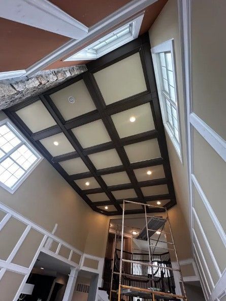 Tall atrium with a paneled ceiling, skylights, and a spiral staircase under renovation
