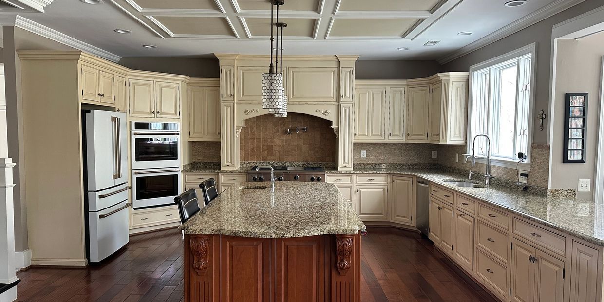 Bright kitchen with cream cabinets, granite island, stainless appliances, and large windows