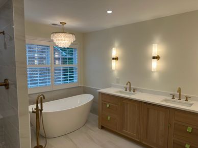 Elegant bathroom with a freestanding tub, double vanity, and chandelier-lit window seating area