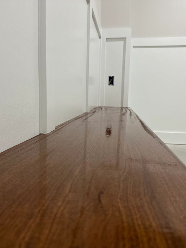 Low-angle view down a glossy wooden hallway with white walls and doors.