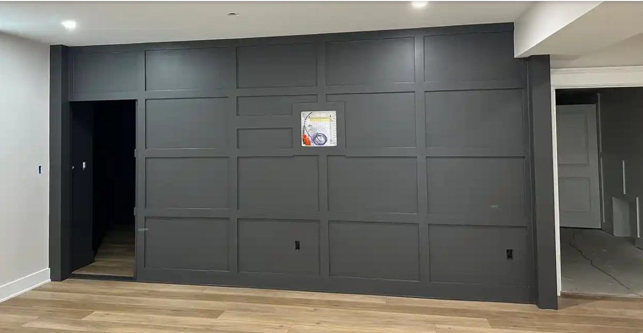 Empty room with dark paneled wall, open doorway, and light wood floor.