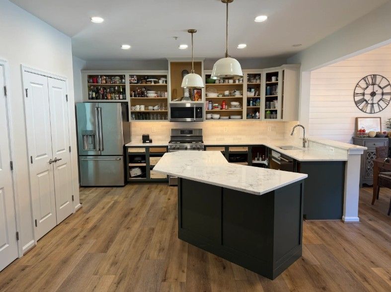 Modern kitchen with white cabinets, stainless refrigerator, island, and wood flooring