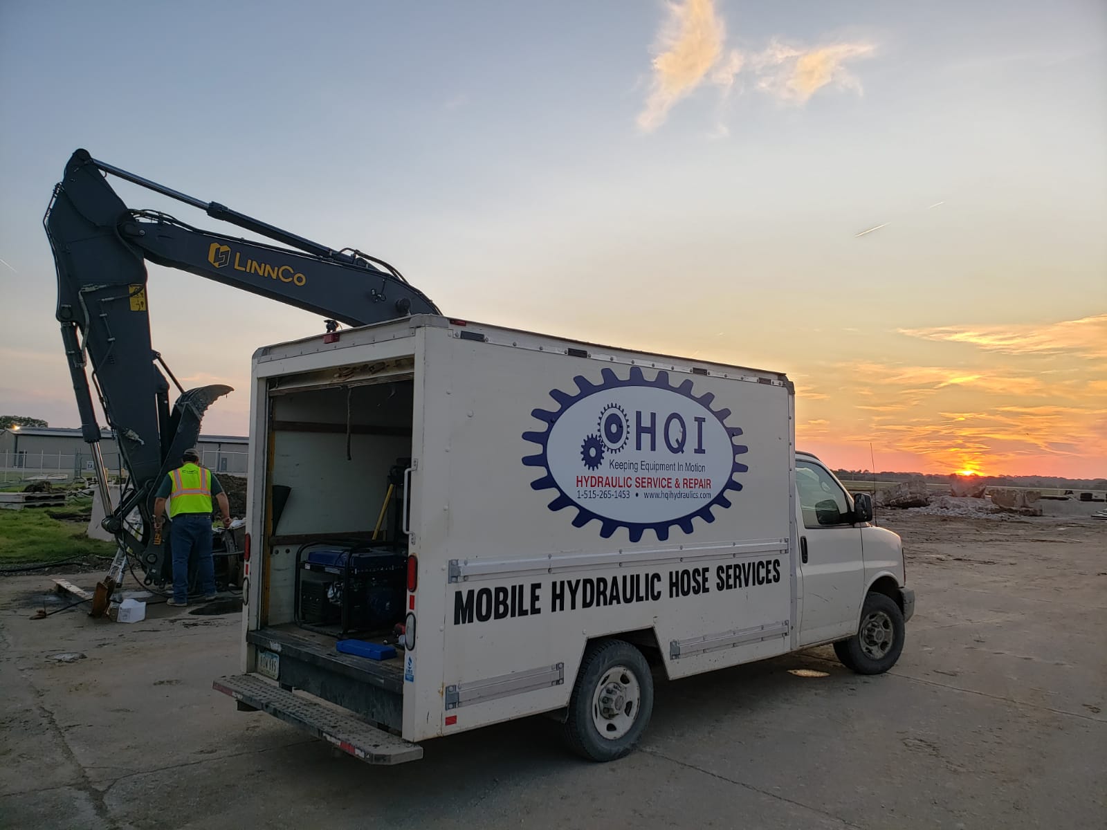A picture of HQI Hydraulics mobile service van and mobile service technician. The HQI Hydraulics service van is in the foreground while the service tech works on an excavator boom in the background. The setting sun provides a lovely backdrop for this image. 