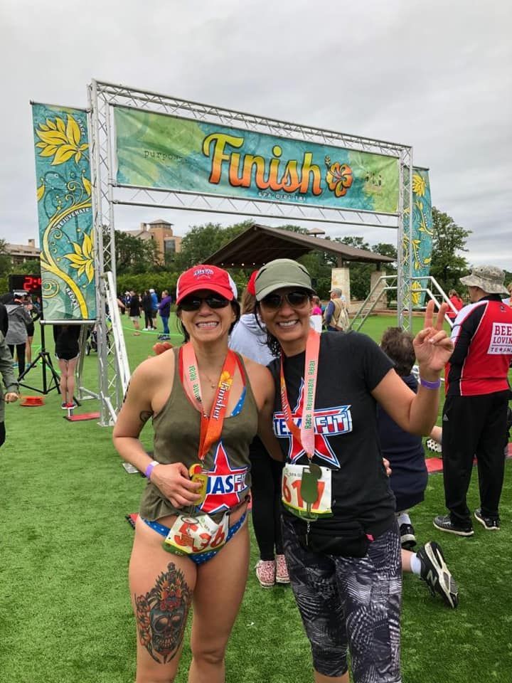 Two women are posing for a picture in front of a finish line sign.