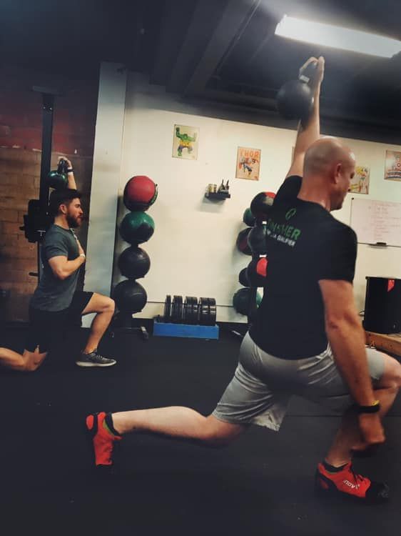 Two men are doing exercises in a gym and one of them is wearing a shirt that says power