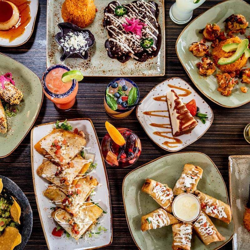 A table topped with plates of Mexican food and drinks.