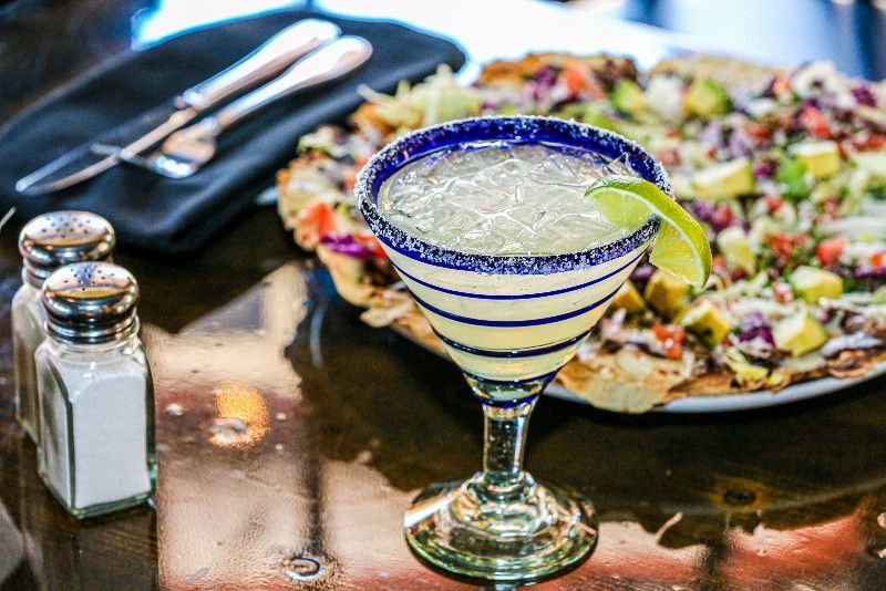 A margarita is sitting on a table next to a plate of nachos.
