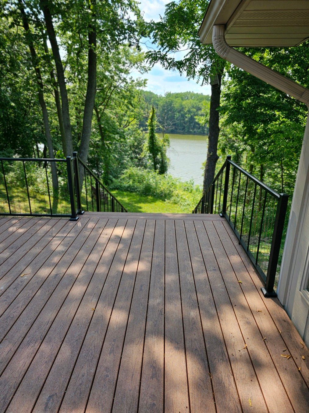 A wooden deck with a view of a lake surrounded by trees