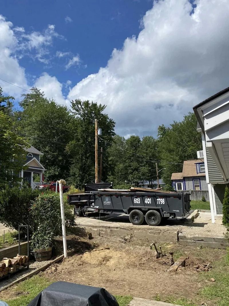 Dumpster on a construction site, next to a house, under a cloudy sky.