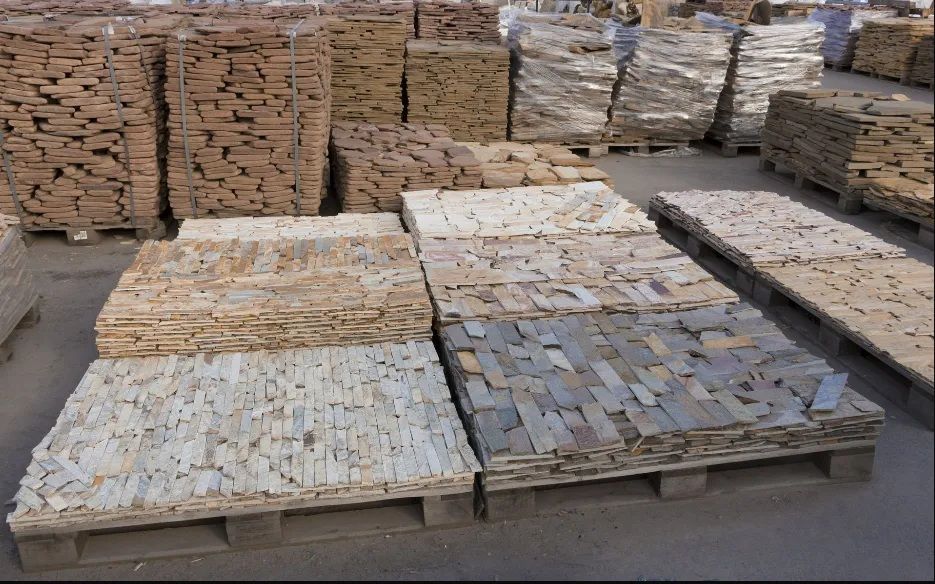 Stacks of assorted paving stones and bricks on wooden pallets in a storage yard