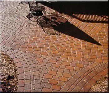 Curved brick walkway with a bicycle and its shadow in sunlight