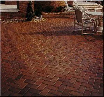 Brick patio with herringbone paving, bordered by outdoor café tables and chairs at the edge of a walkway