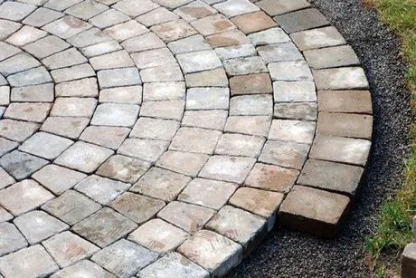 Curved stone paver patio with concentric rings beside a gravel and grass edge