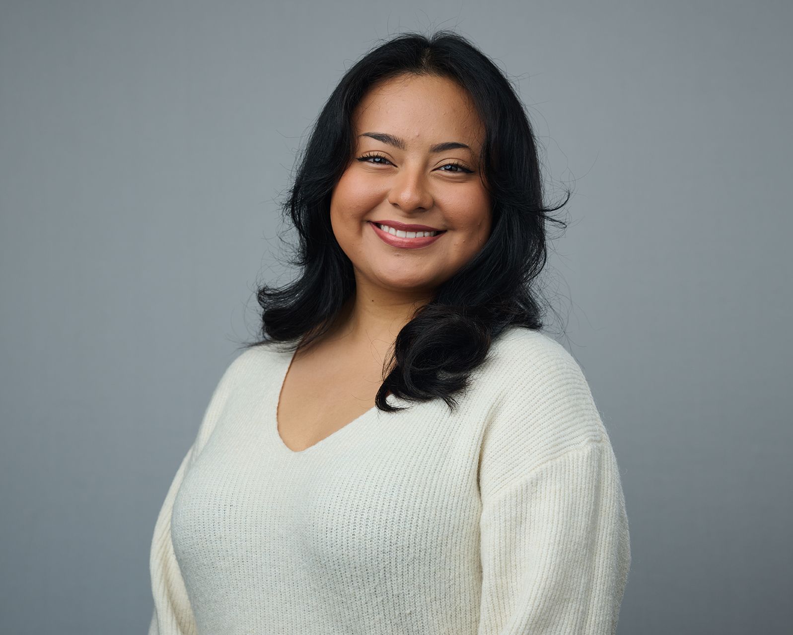 A woman in a white sweater is smiling for the camera.