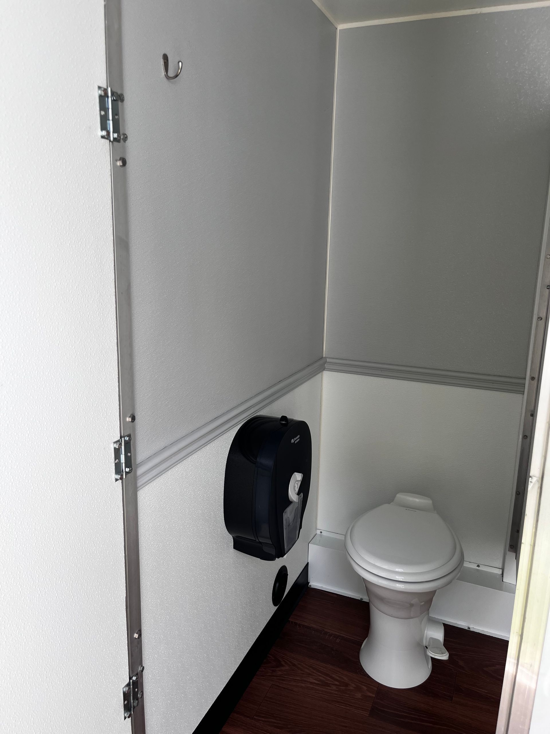 Small restroom with a white toilet, gray walls, and a black paper towel dispenser.