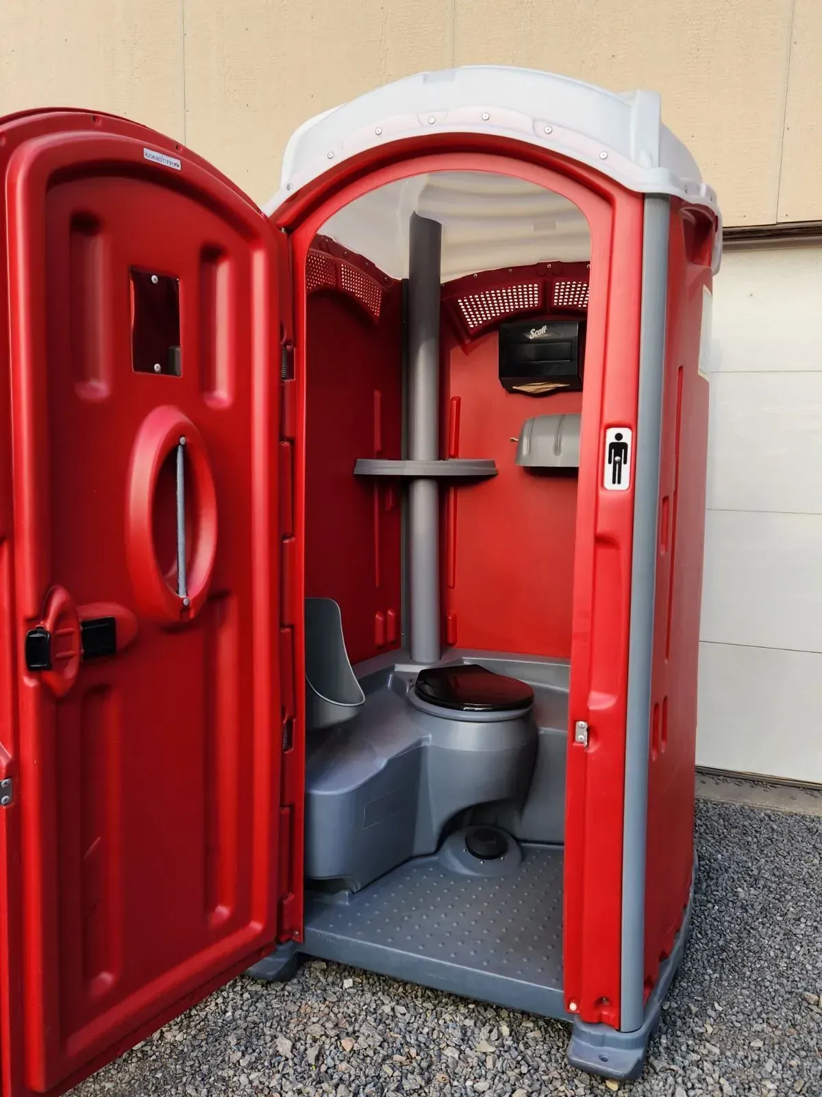 Red and gray portable toilet with the door open, showing the interior with a toilet seat and a central support.