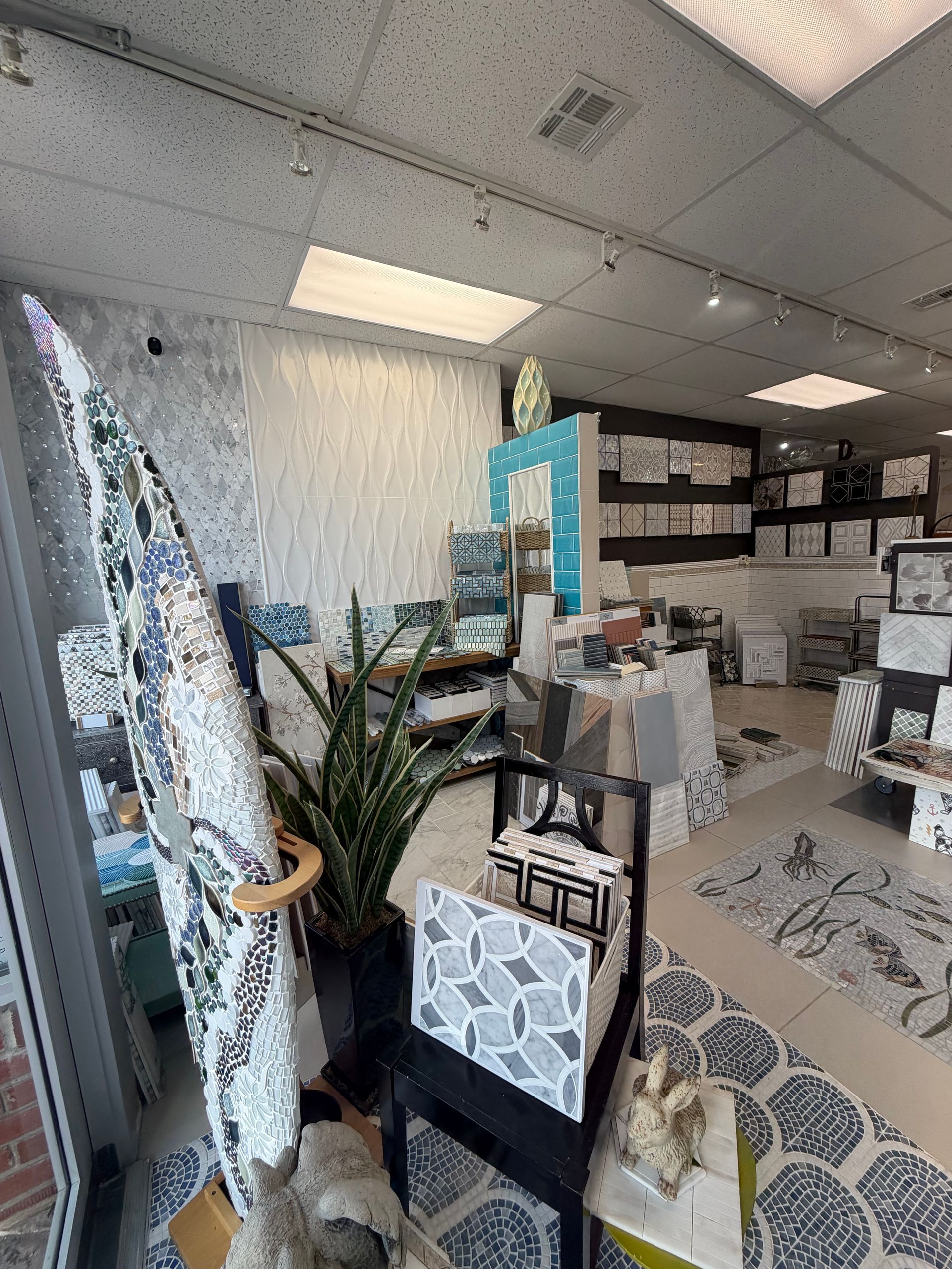 Interior of a cluttered home decor shop with surfboards, plants, rugs, and shelves of merchandise.