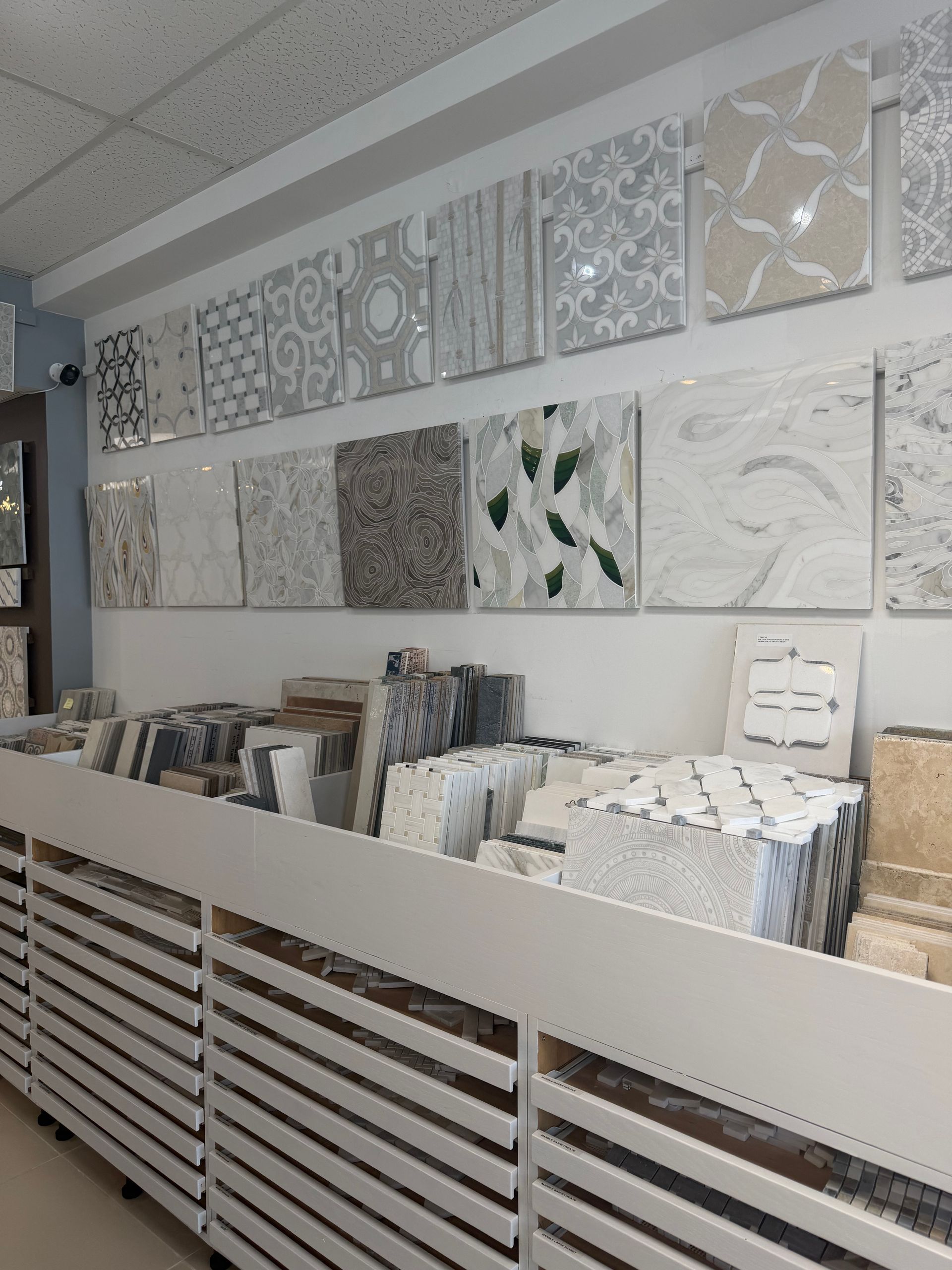 Tile showroom display with patterned wall samples and bins of tile swatches on shelves