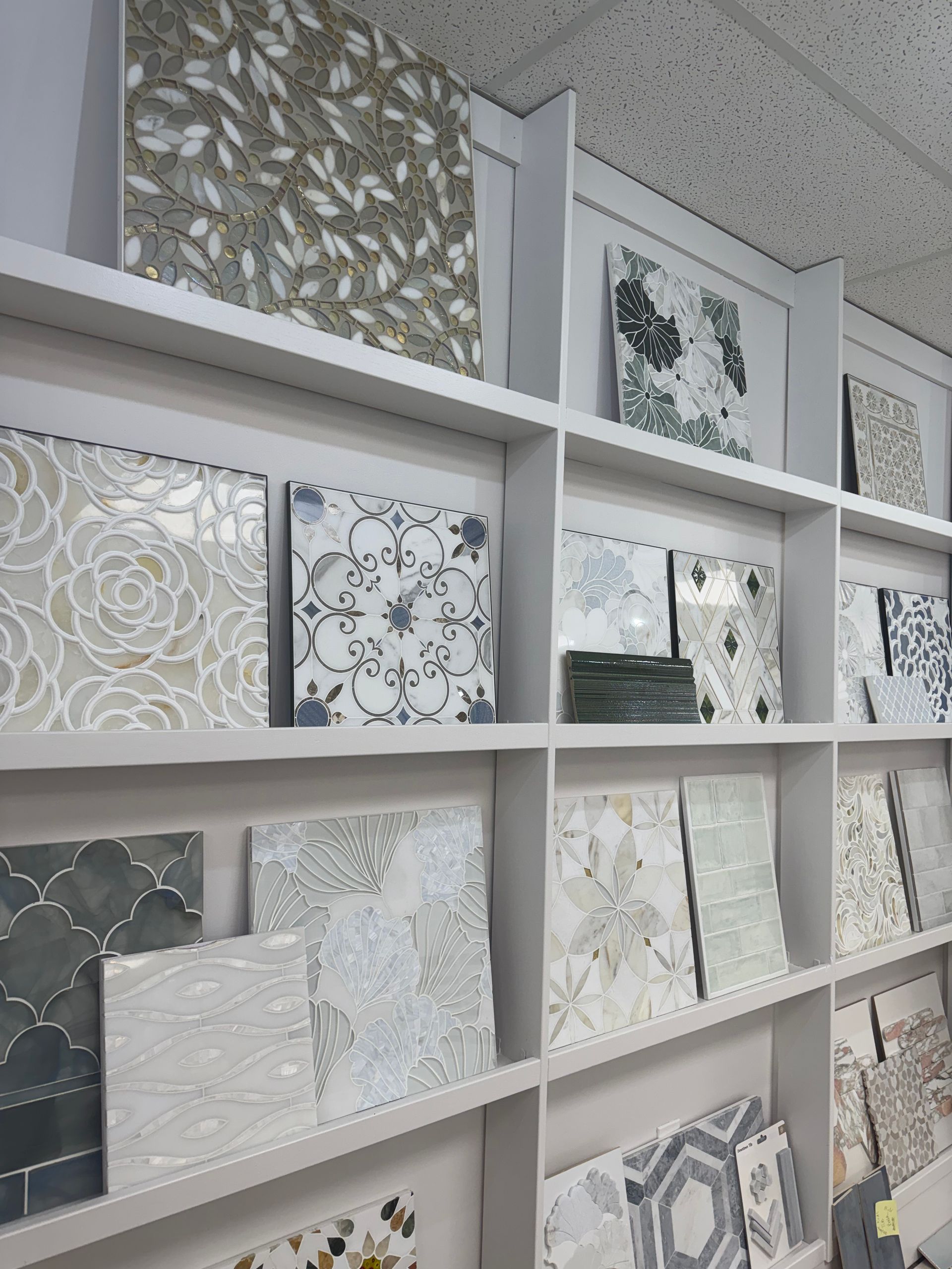 Shelves of decorative tile samples in gray, white, and black patterns at a showroom