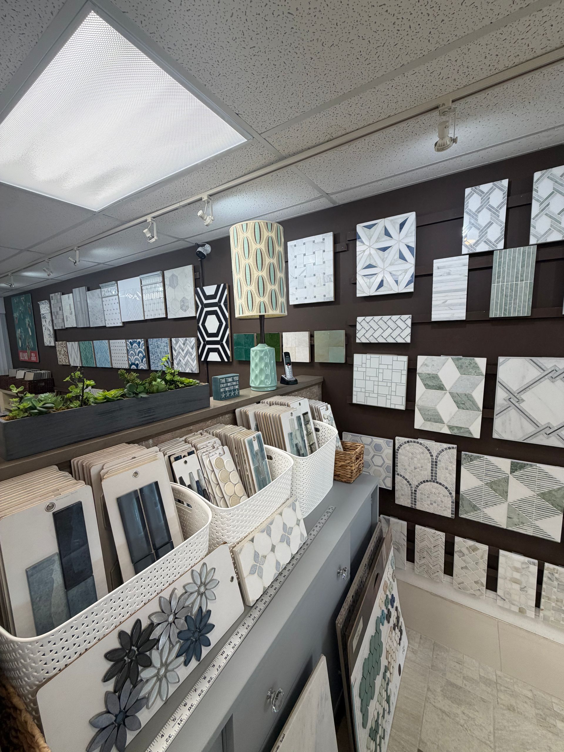 Showroom with patterned wallpaper samples displayed on wall and fabric swatches draped on tables