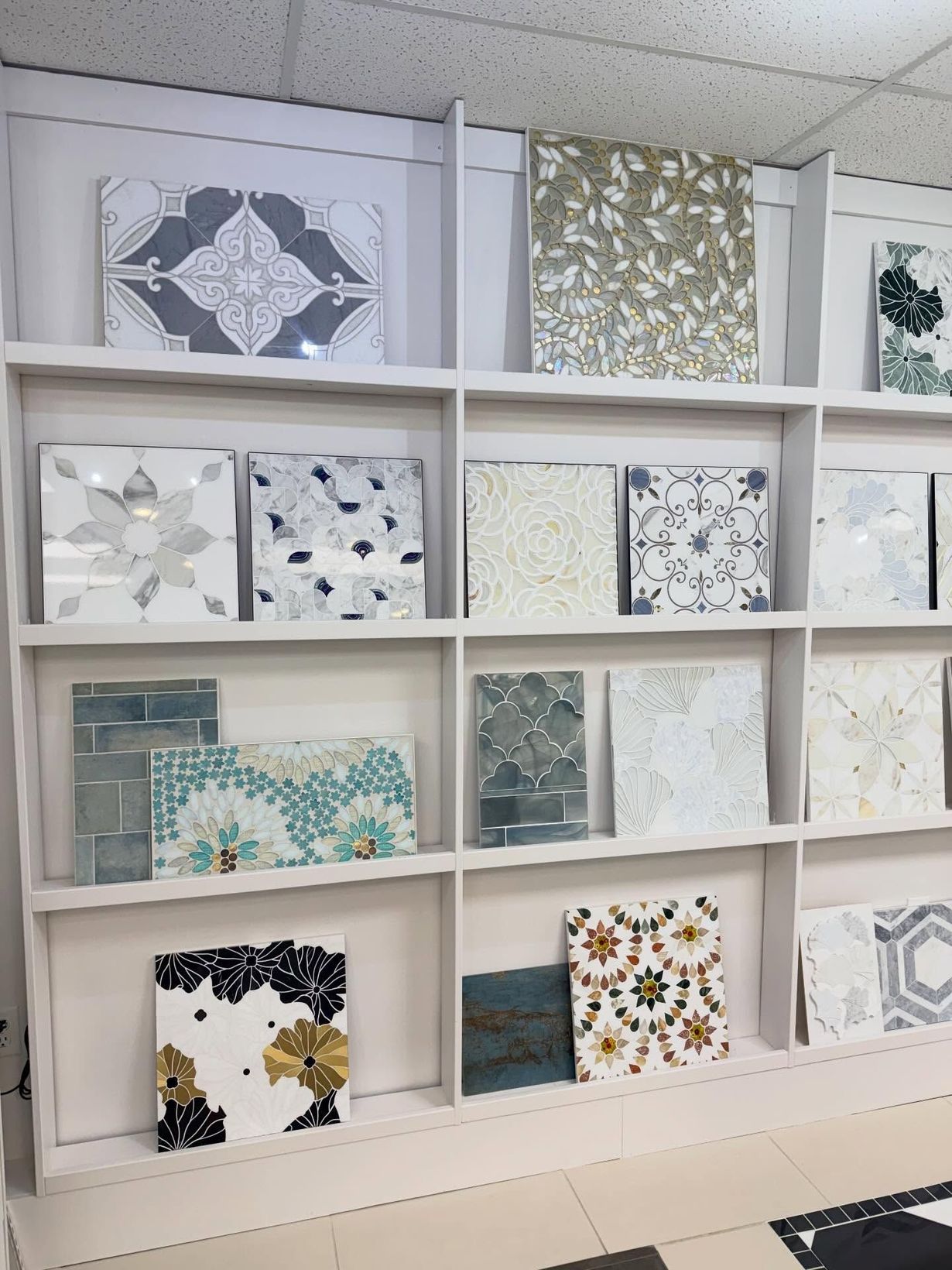 Display of decorative mosaic tile samples in a white shelving unit