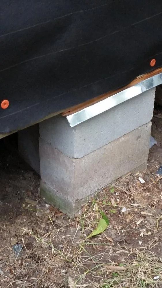 Black tarp or fabric draped over stacked gray concrete blocks on dirt outdoors