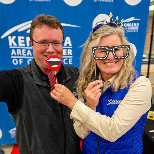 A man and a woman are posing for a picture with a fake mouth and glasses.