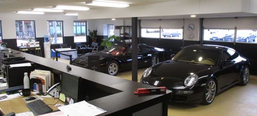 A black porsche is parked in a showroom