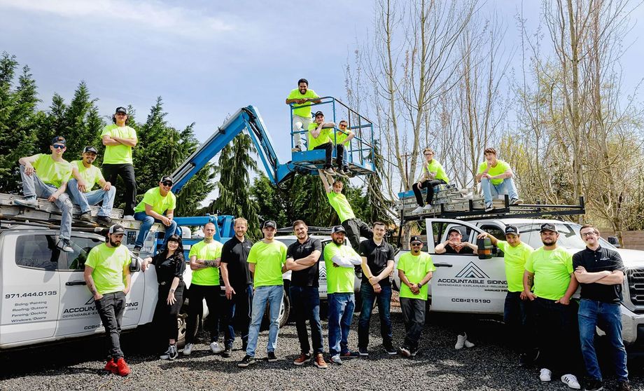 A group of construction workers are posing for a picture in front of their trucks.