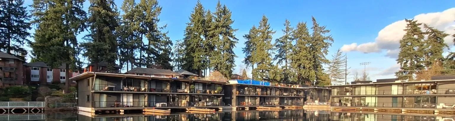 A large building is sitting next to a body of water surrounded by trees.