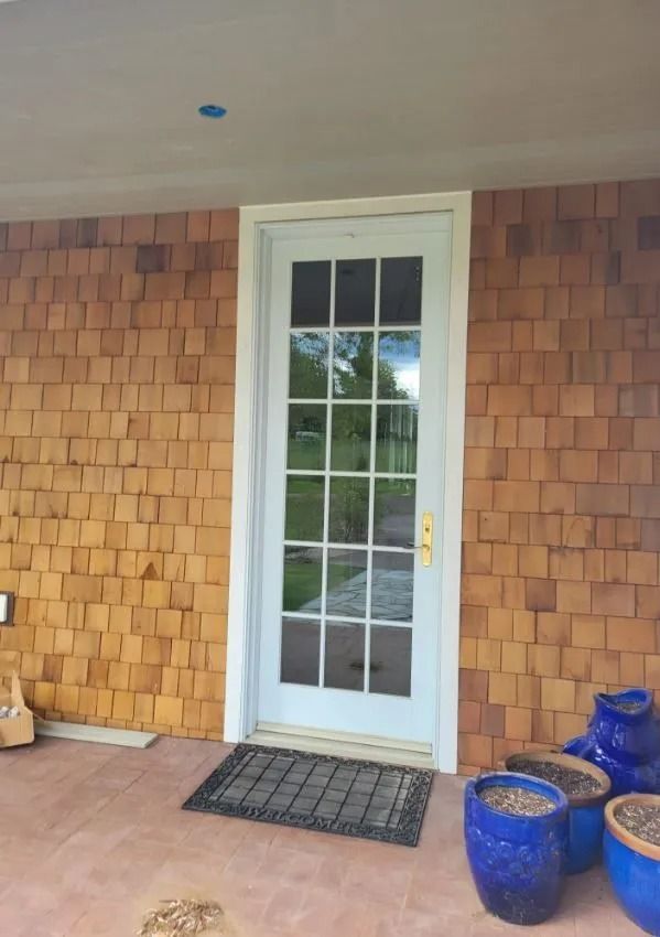 A white door is sitting on a porch next to blue pots.