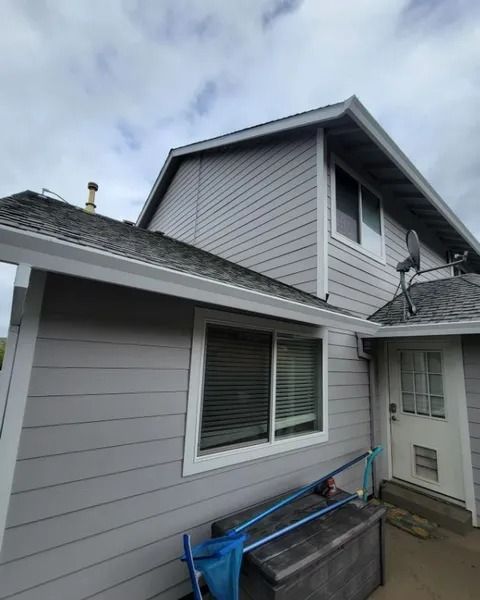 A large gray house with a satellite dish on the roof.