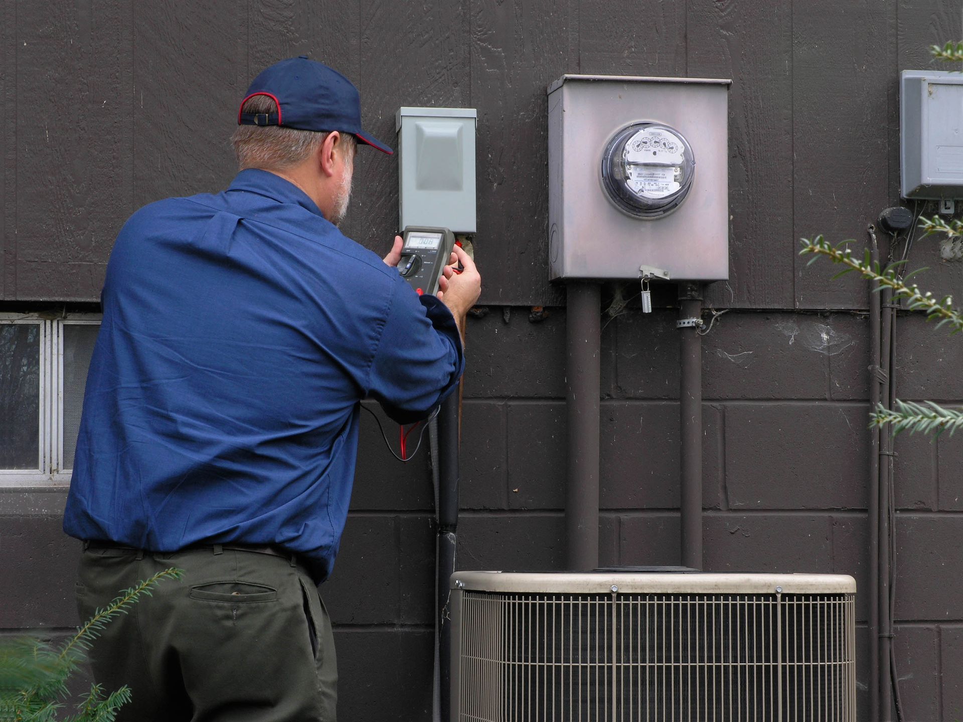 Utility worker inspecting outdoor meter panel on a building wall