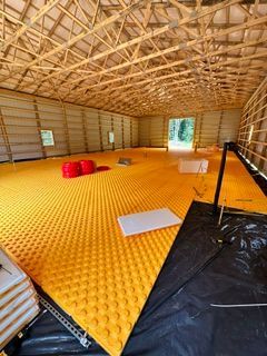 Empty bamboo hut with a bright yellow floor mat, woven ceiling, and a few red cushions inside